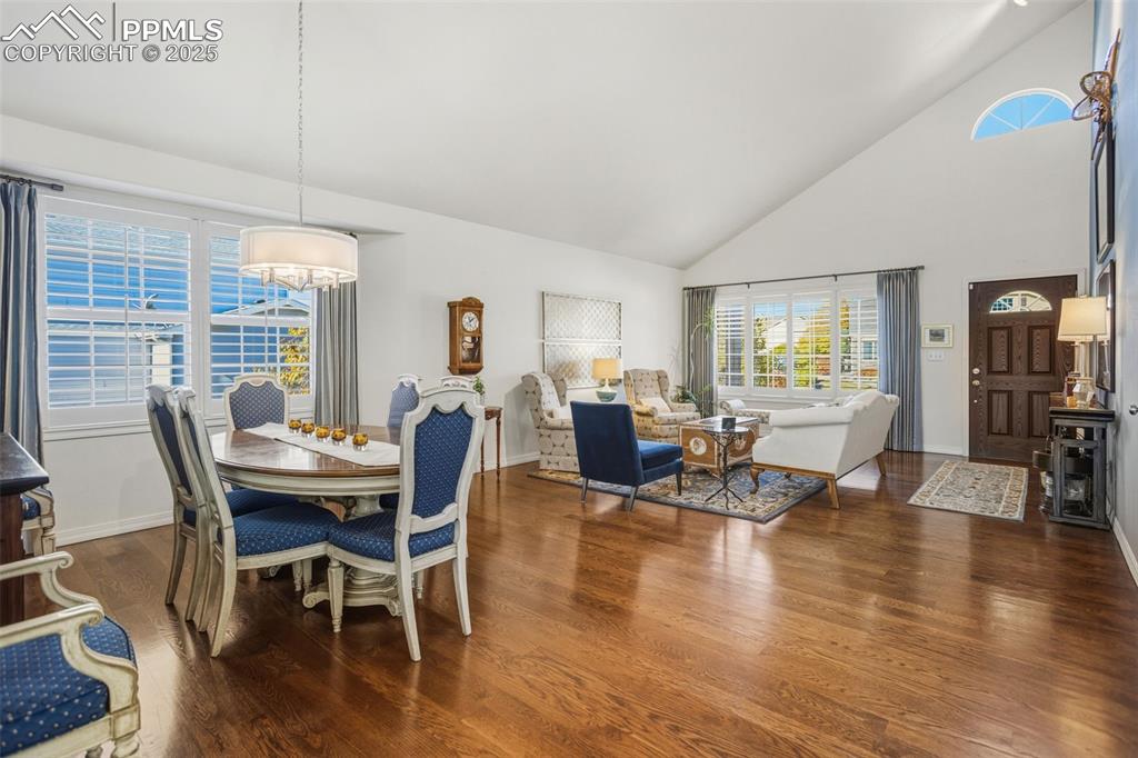 Image 15 of 43: Dining area with high vaulted ceiling and dark wood-type flooring
