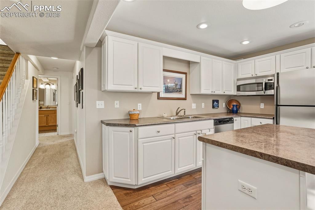 Image 17 of 43: Kitchen with stainless steel appliances, white cabinets, dark countertops, 