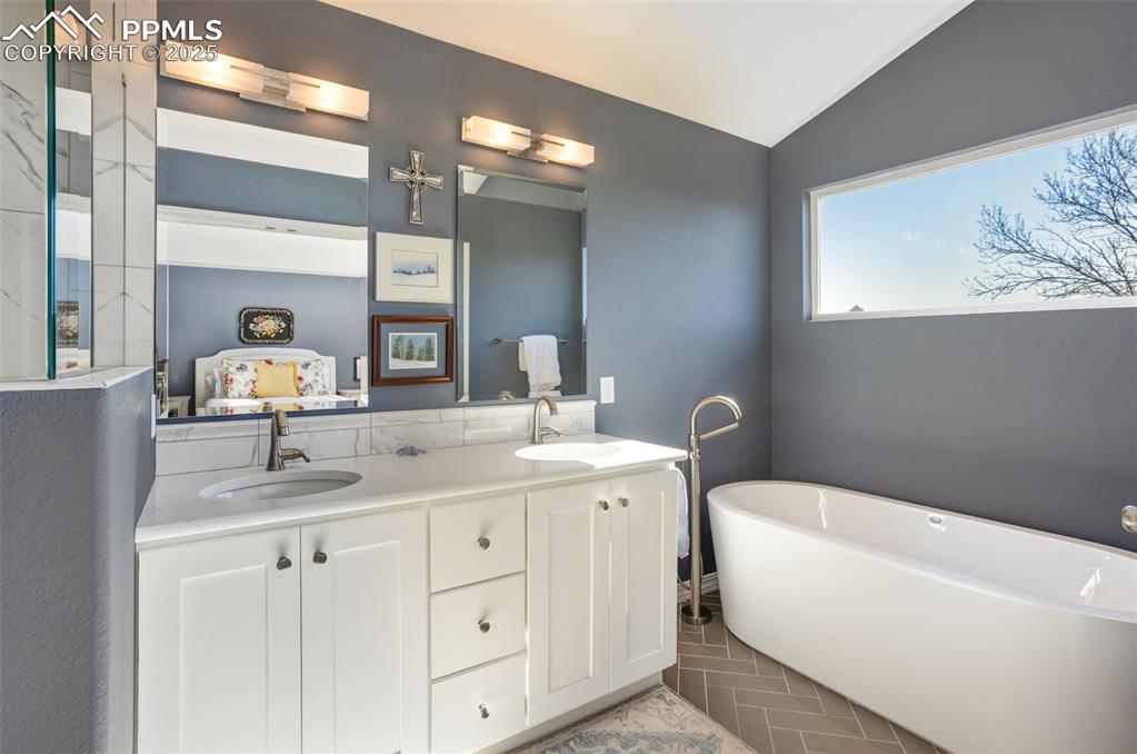 Image 27 of 43: Bathroom featuring vaulted ceiling, double vanity, a freestanding bath, ens