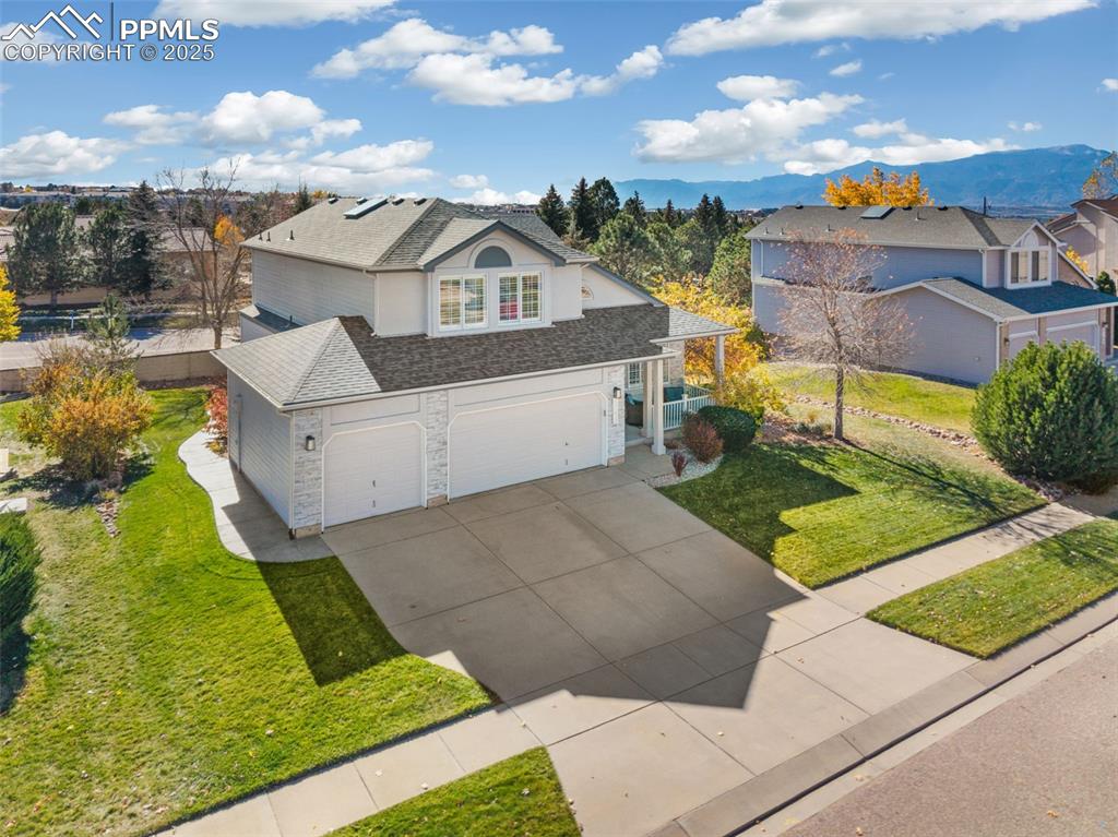 Image 3 of 43: View of front facade with a front lawn, a shingled roof, concrete driveway,