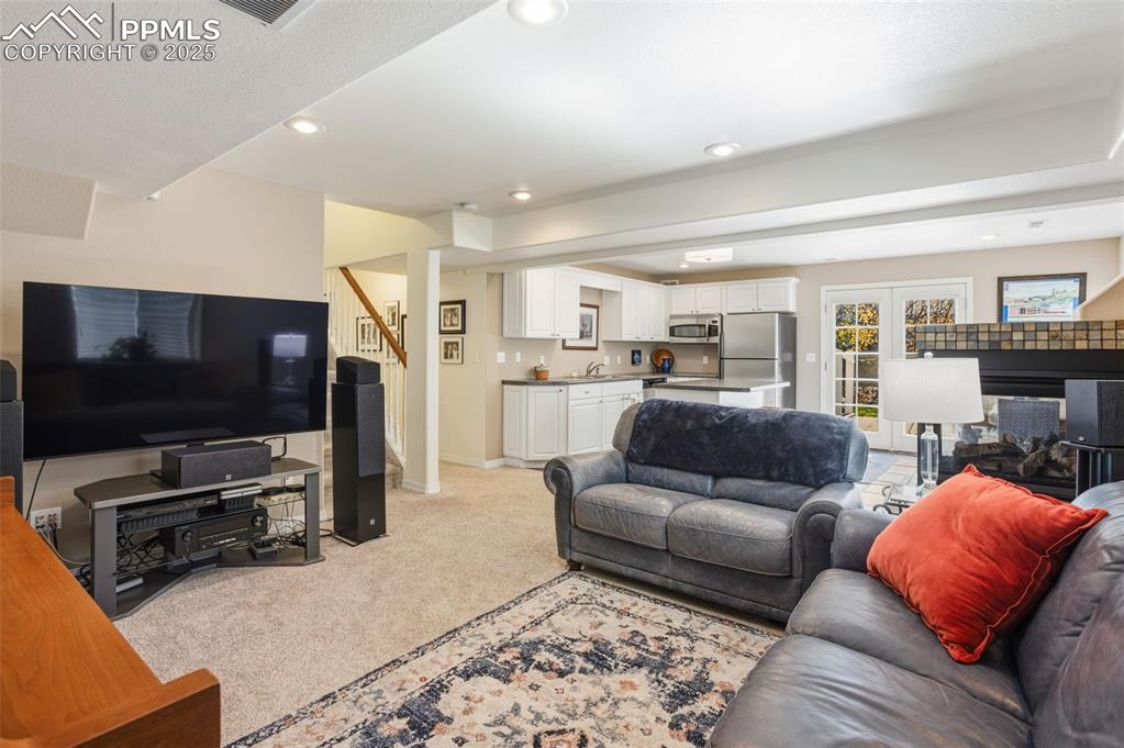 Image 38 of 43: Living room with light carpet, recessed lighting, and stairs