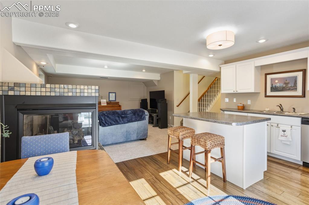 Image 39 of 43: Kitchen with a kitchen bar, open floor plan, white cabinetry, a kitchen isl