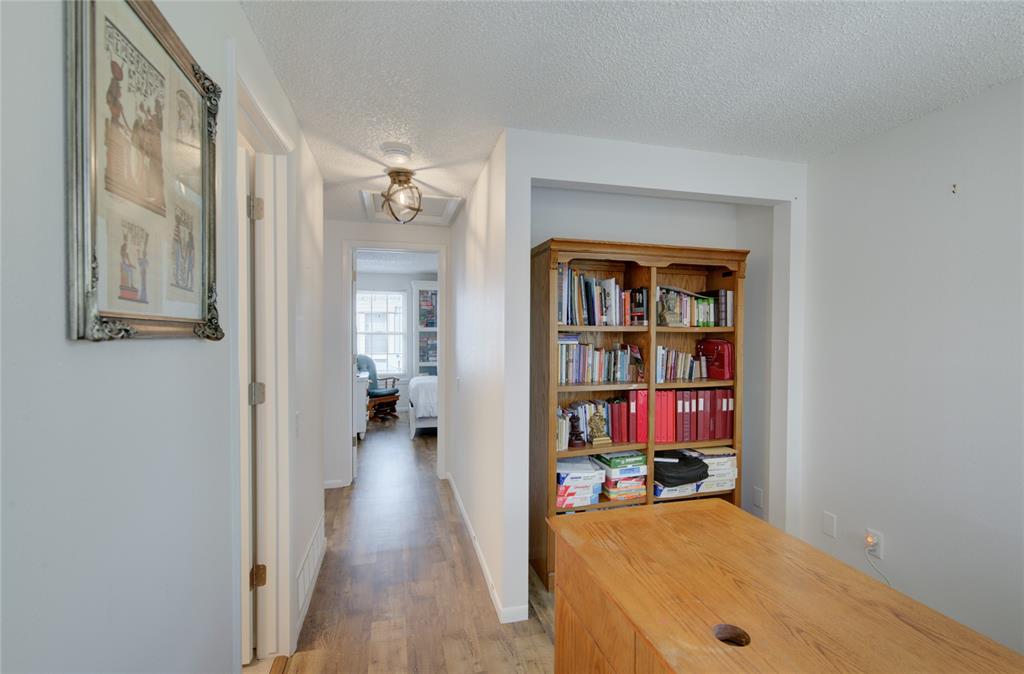Image 11 of 21: Hallway with wood-finish flooring, white walls, and a built-in recessed woo