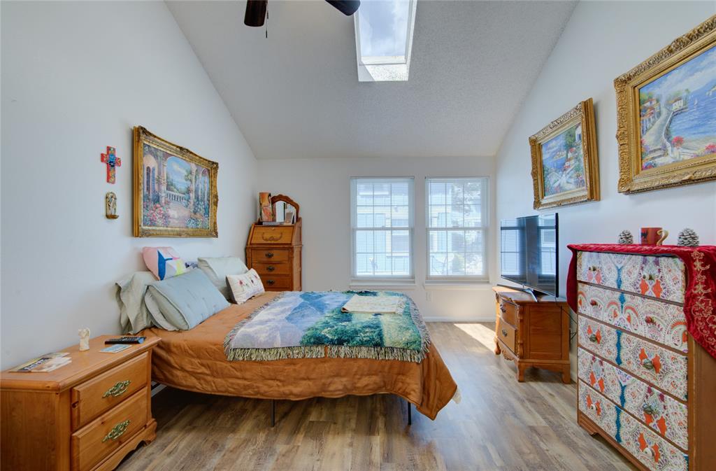 Image 13 of 21: Vaulted ceilings with a skylight, wood-finish flooring, and white walls wit