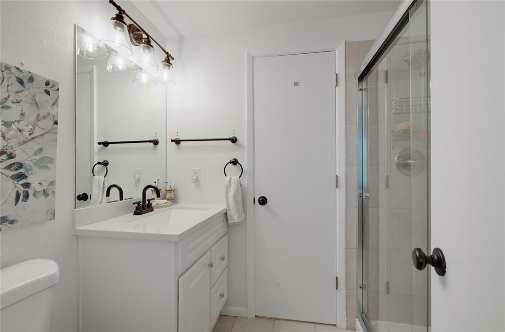 Image 16 of 21: Bathroom featuring a white vanity with a single sink, an overhead bronze-fi