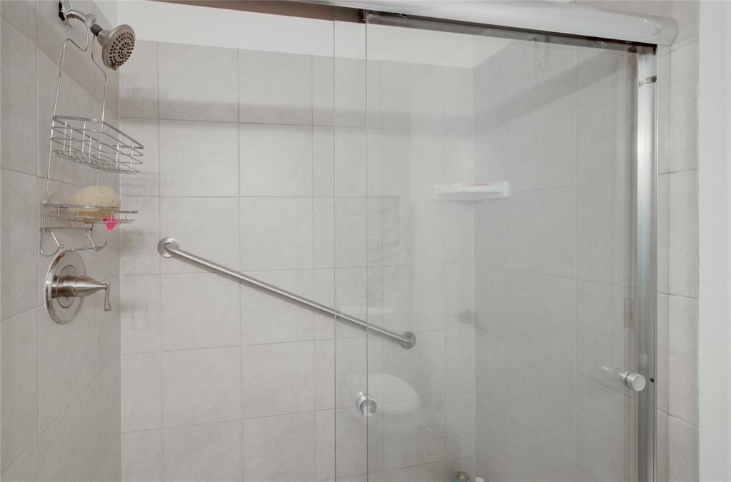 Image 17 of 21: Shower enclosure featuring light-toned square wall tiles