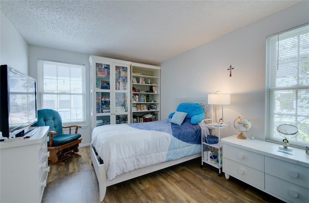 Image 18 of 21: Bedroom featuring wood-finish flooring, two window units with blinds, and w