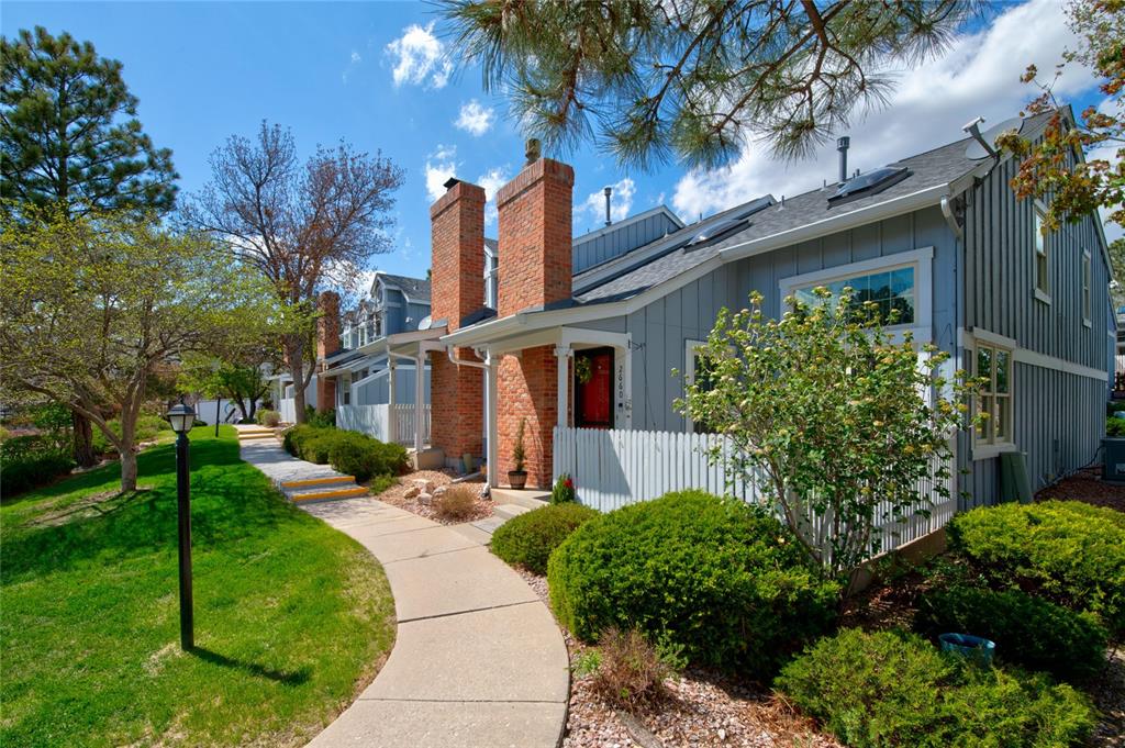 Image 2 of 21: Townhome exterior featuring brick chimney accents, a white picket fence, an