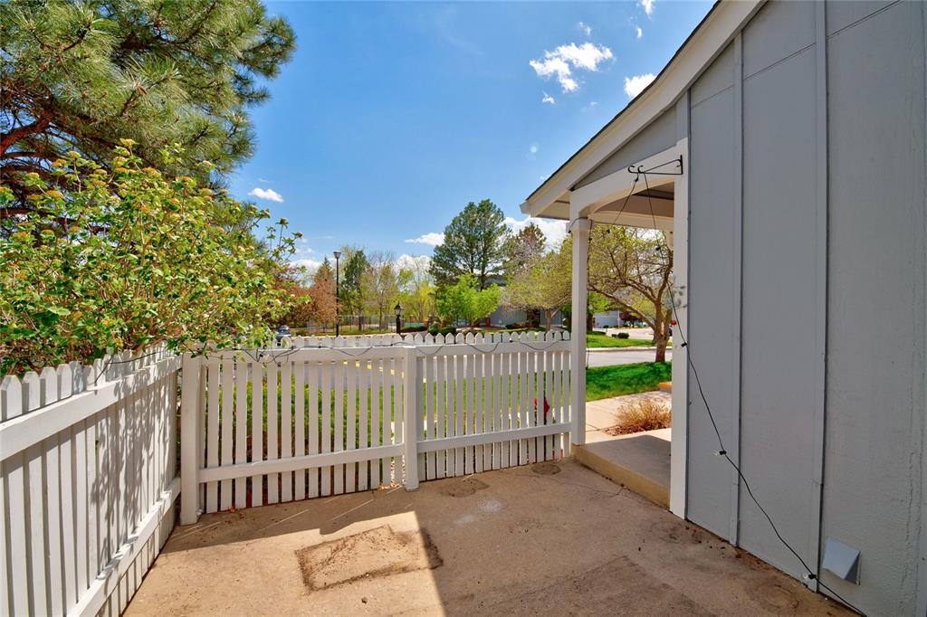 Image 20 of 21: Picket fence enclosed patio with concrete flooring, accented by mature tree