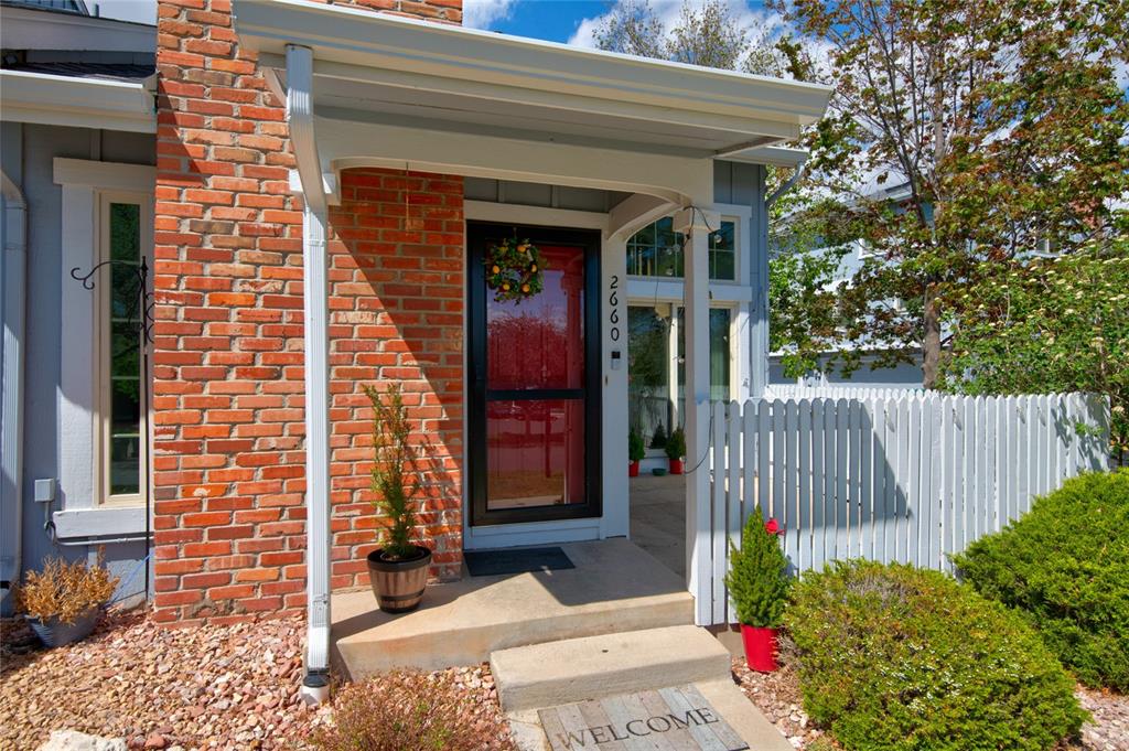 Image 3 of 21: Brick facade with light gray siding, covered entry porch, and a red front d