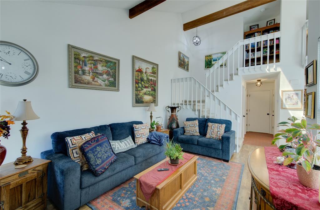 Image 5 of 21: Vaulted ceilings with exposed wood beams, a prominent staircase with white 