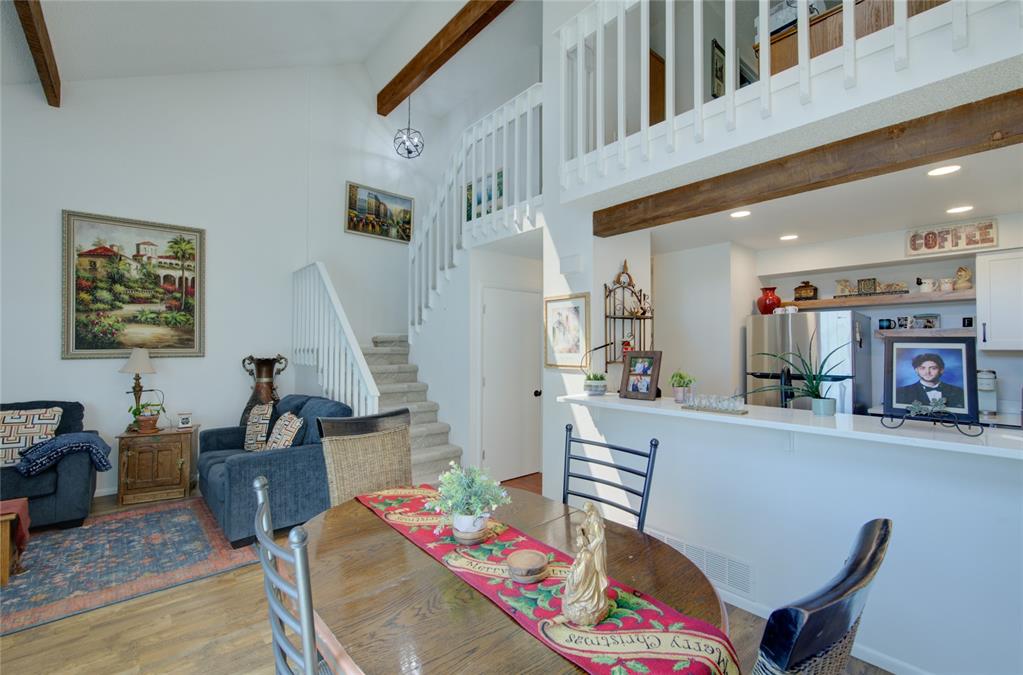 Image 7 of 21: Vaulted ceiling living space featuring exposed wood beams and a white spind