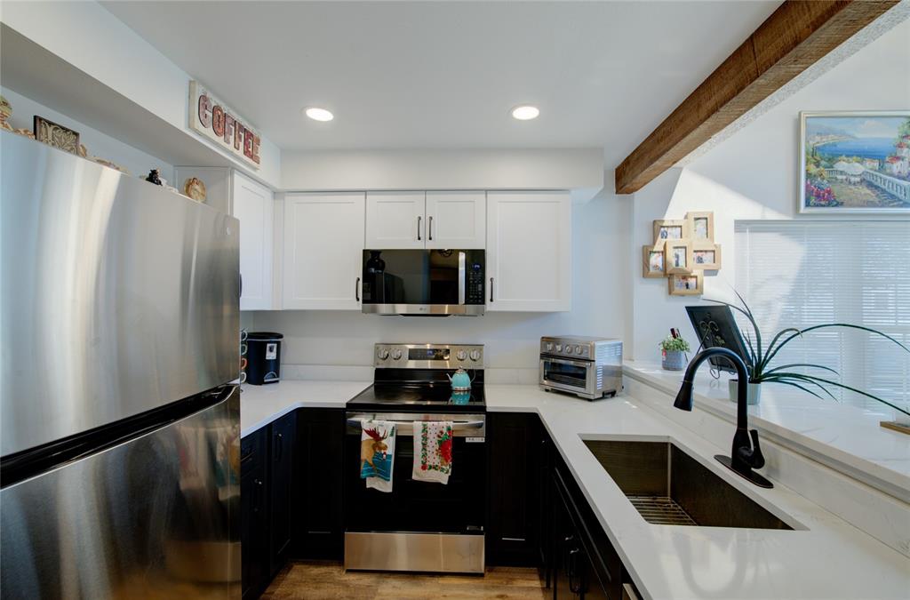 Image 8 of 21: Kitchen featuring white upper cabinetry, dark lower cabinetry, stainless st