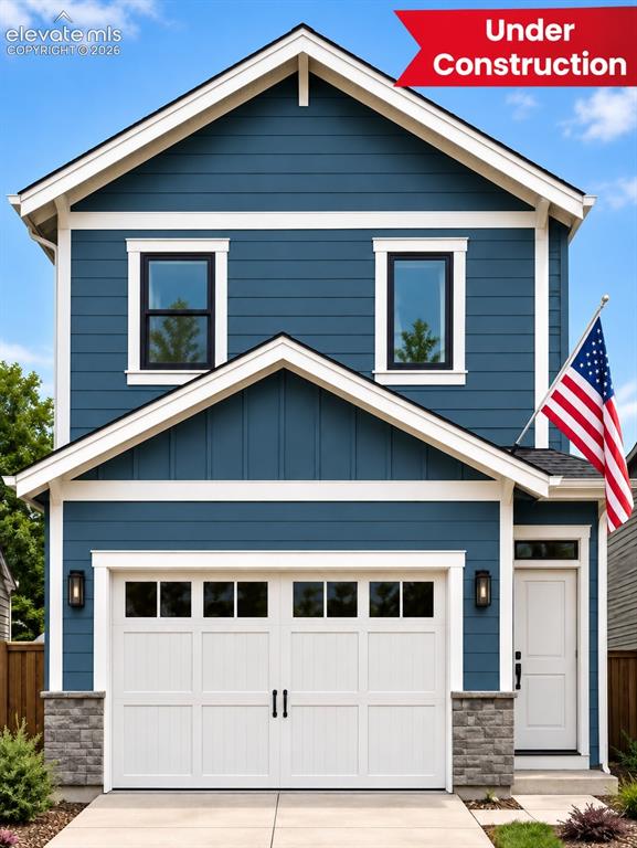 Caption: Deep blue siding, white trim accents, attached garage with carriage-style doors, stone veneer detail