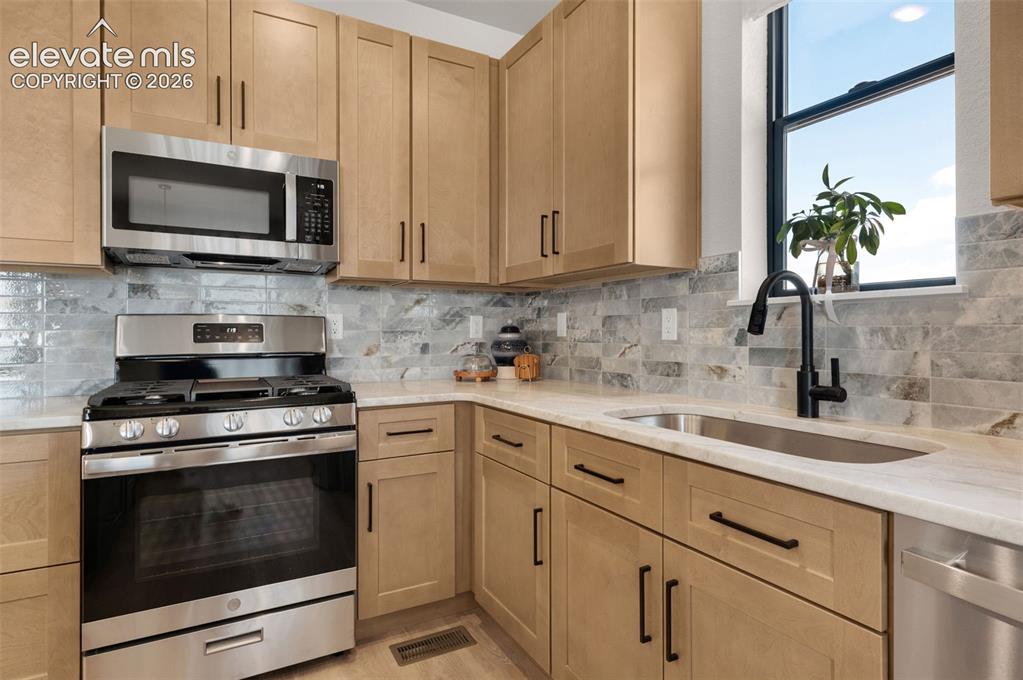 Image 12 of 36: Light-toned cabinetry with matte black hardware, stainless steel appliances