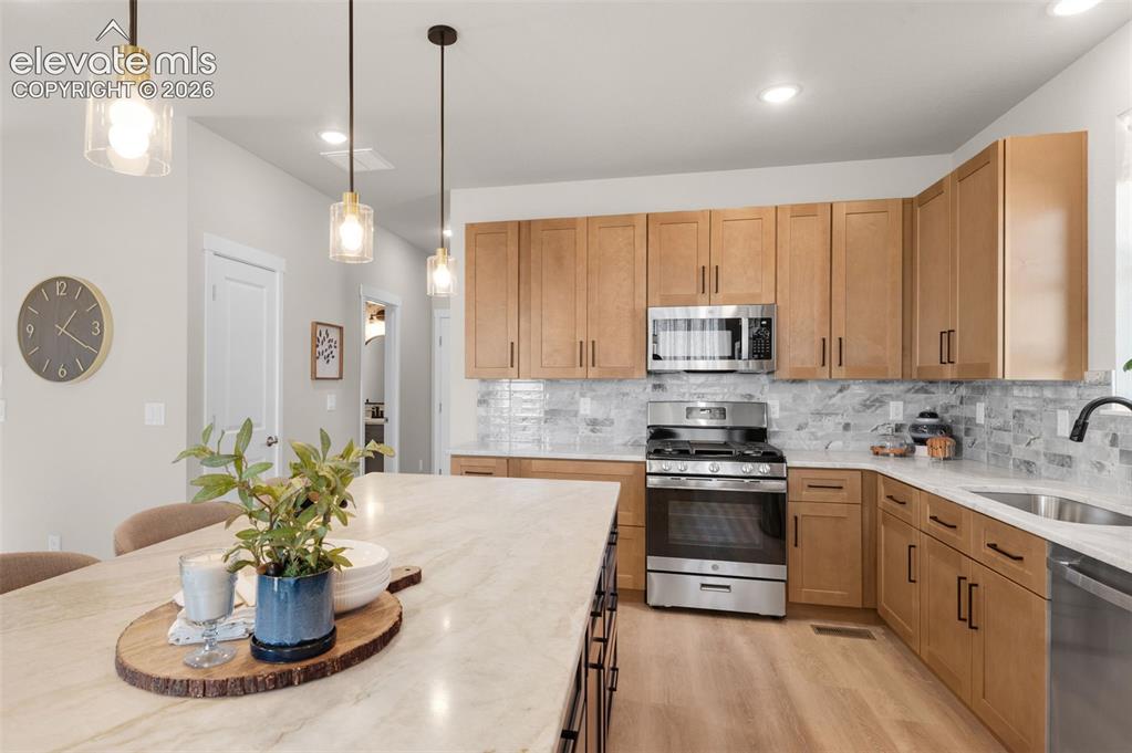 Image 13 of 36: Kitchen featuring wood-finish cabinetry, stainless steel appliances, a tile