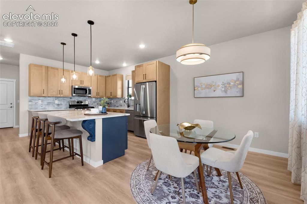Image 14 of 36: Open-concept kitchen and dining area featuring wood-finish flooring, recess