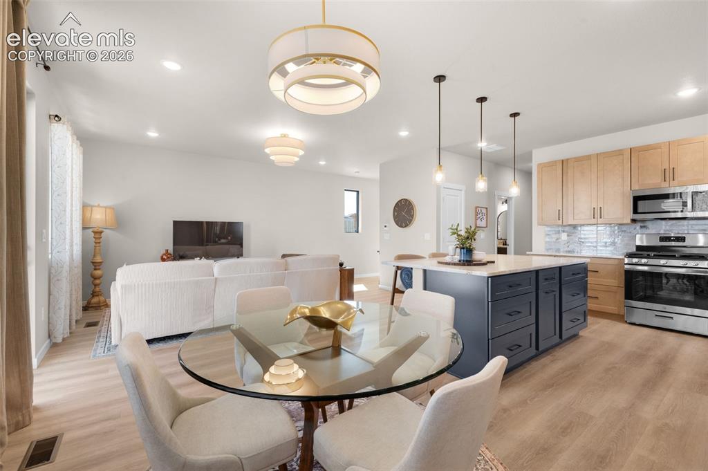 Image 15 of 36: Open-concept living space featuring wood-finish flooring, recessed lighting