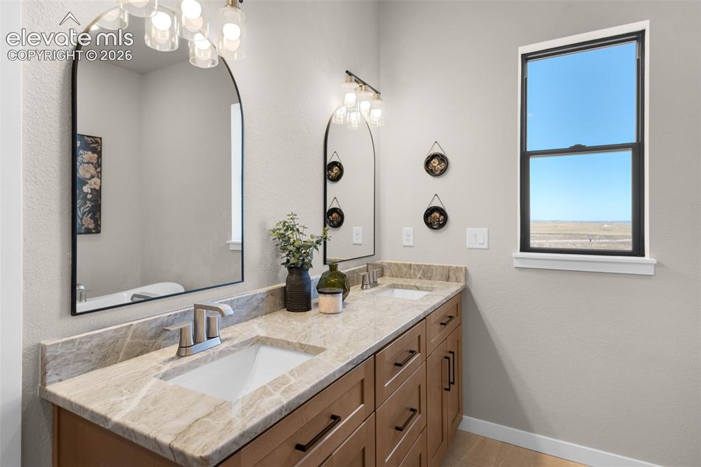 Image 23 of 36: Dual vanity with undermount sinks, light-toned countertop, and wood-finish 