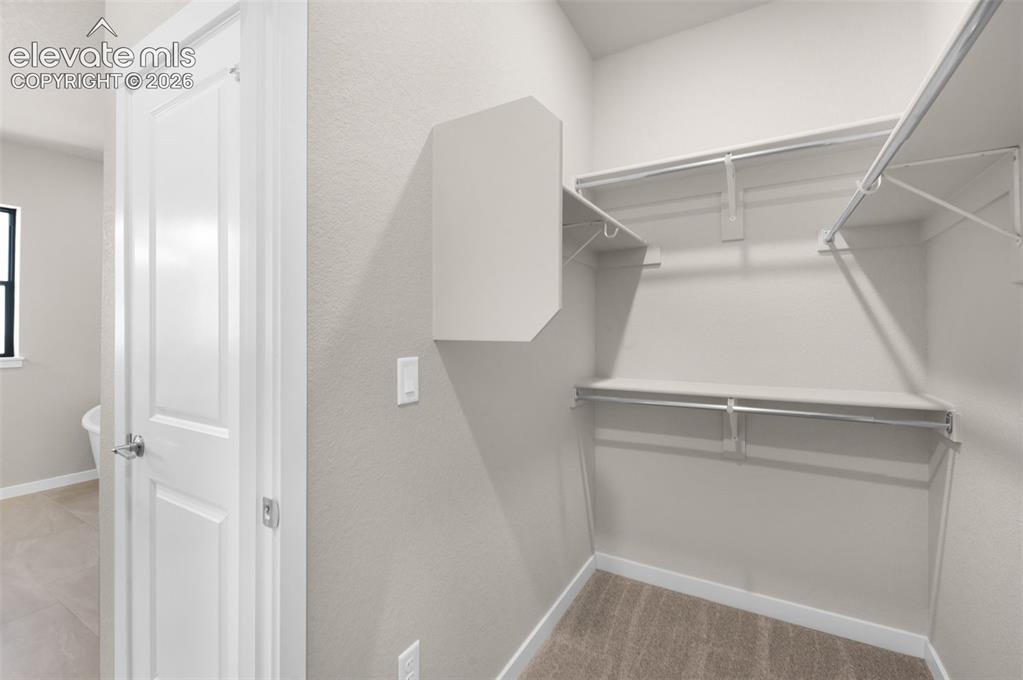 Image 24 of 36: Walk-in closet with wire shelving, integrated hanging rods, and neutral car