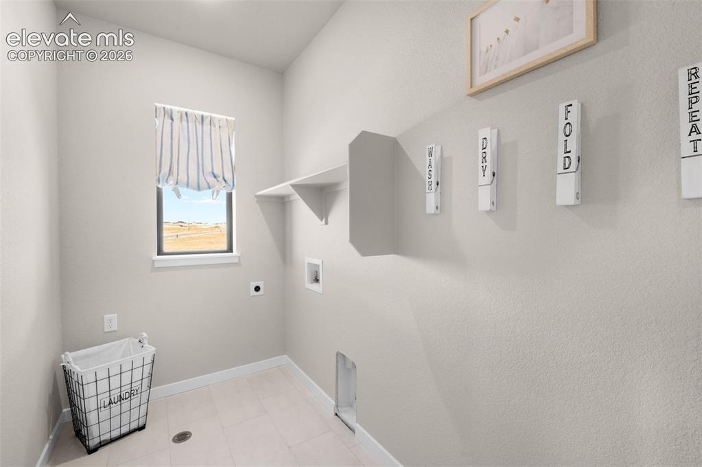 Image 30 of 36: Laundry area featuring a window, built-in shelving, and light-toned floorin
