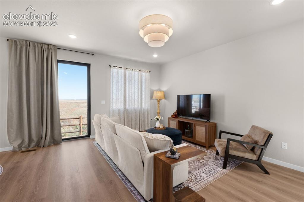 Image 4 of 36: Wood-finish flooring, recessed lighting, and a tiered chandelier illuminate