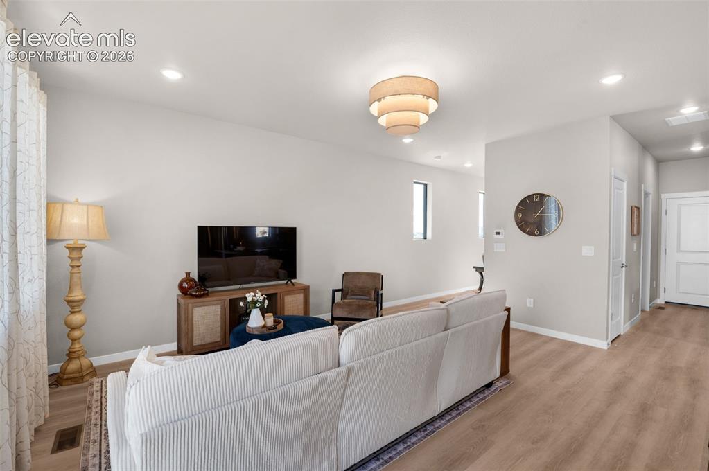 Image 5 of 36: Recessed lighting, wood-finish flooring, and a contemporary tiered light fi