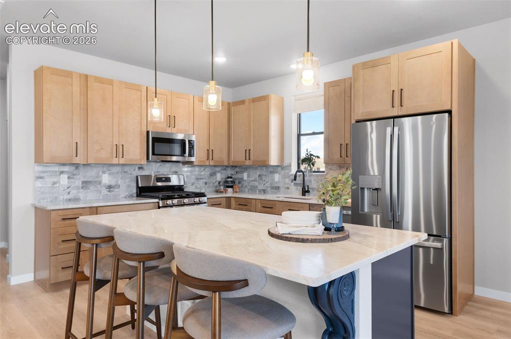 Image 8 of 36: Kitchen featuring a central island with a light-toned countertop, stainless