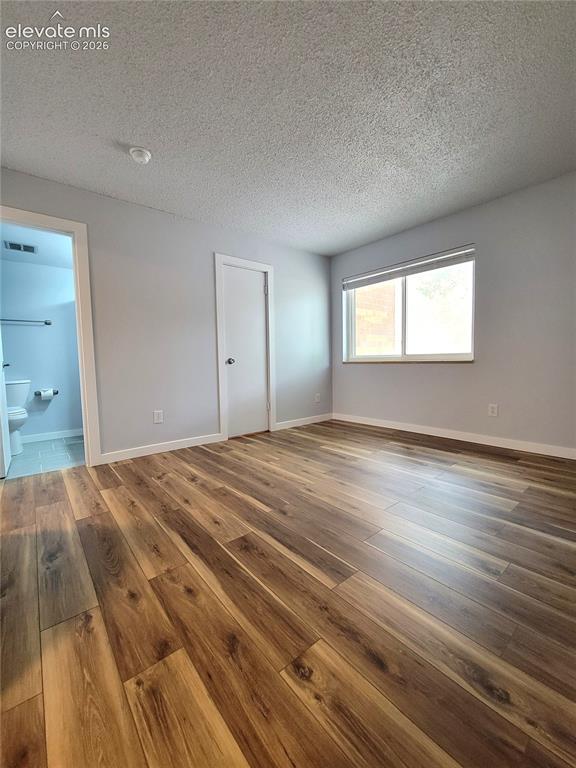 Image 10 of 31: Spacious room featuring wood-finish flooring, light grey painted walls, a s