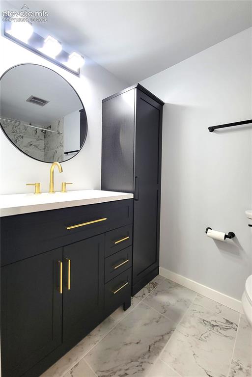 Image 17 of 31: Bathroom featuring a black vanity with gold hardware, white countertop, and