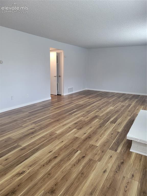 Image 20 of 32: Expansive room featuring wood-finish flooring, light gray walls, white base