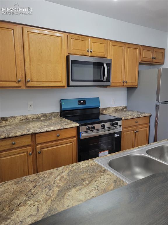 Image 23 of 31: Kitchen featuring wood cabinetry, stainless steel microwave, black electric