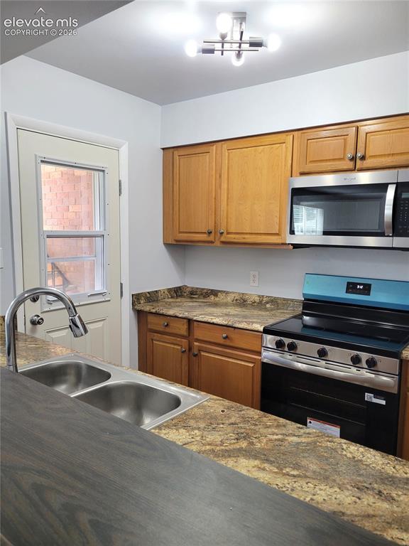 Image 24 of 31: Kitchen featuring wood-finish cabinetry, granite-style countertops, and a d