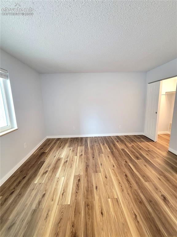 Image 26 of 32: Spacious room featuring wood-finish flooring, light gray walls, and a windo