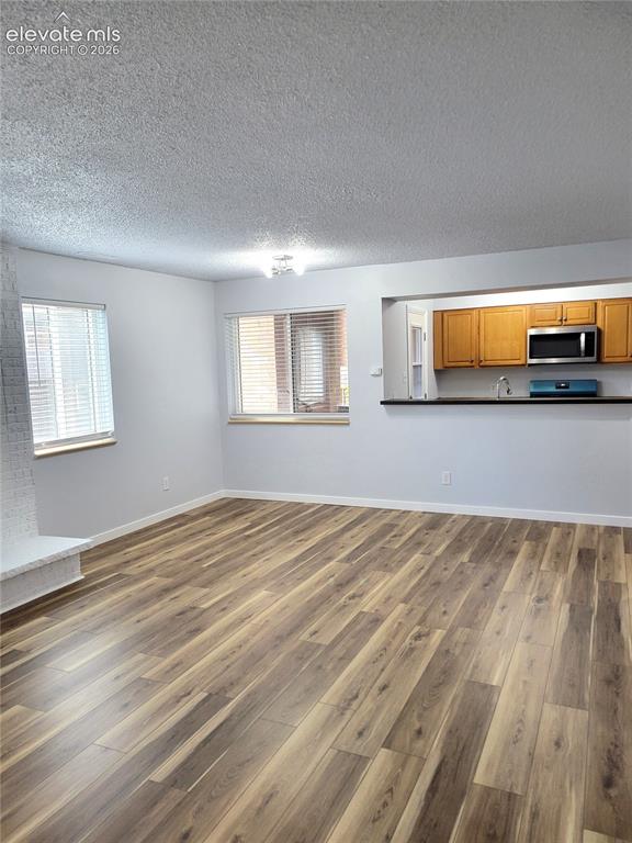 Image 26 of 31: Spacious living area featuring wood-finish flooring throughout