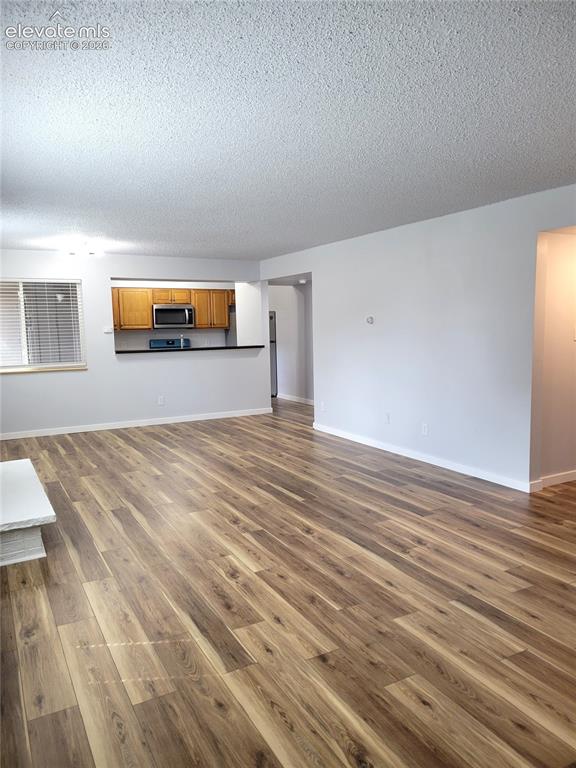 Image 27 of 31: Spacious living area featuring wood-finish flooring throughout