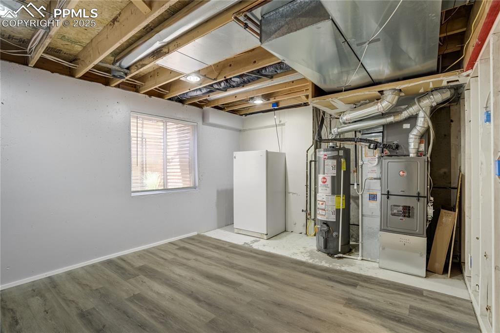 Image 35 of 46: Basement with gas water heater, heating unit, and wood finished floors