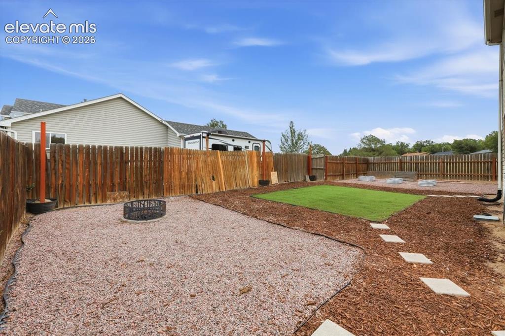 Image 19 of 33: Xeriscaped Fenced Backyard with Firepit, Turf, Raised Garden Boxes, and Sto