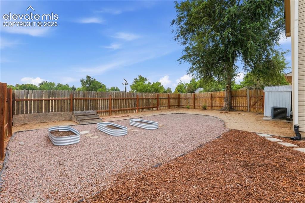Image 20 of 33: Xeriscaped Fenced Backyard with Firepit, Turf, Raised Garden Boxes, and Sto