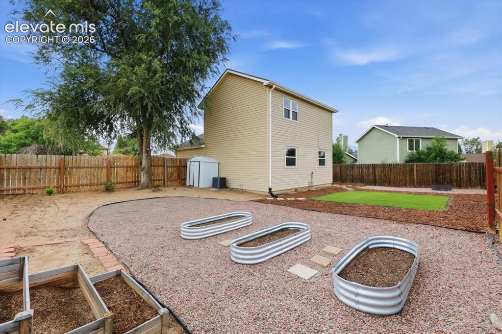 Image 21 of 33: Xeriscaped Fenced Backyard with Firepit, Turf, Raised Garden Boxes, and Sto