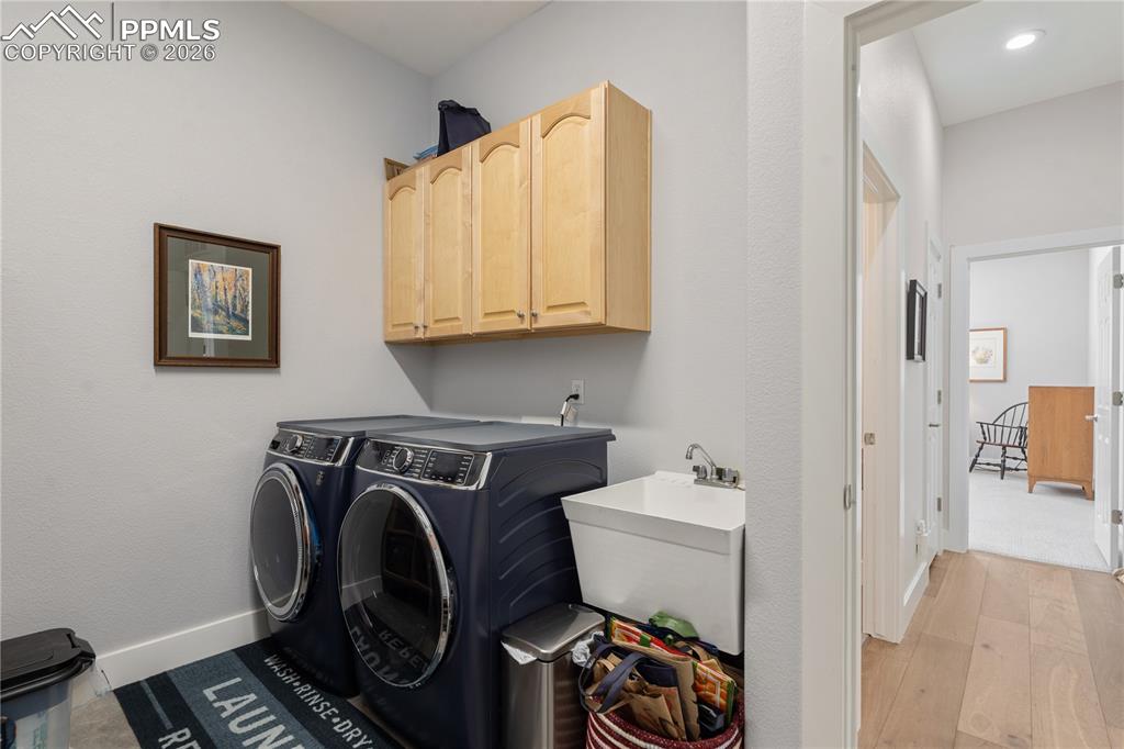 Image 27 of 50: Main level laundry room has cabinets, sink, and door to garage
