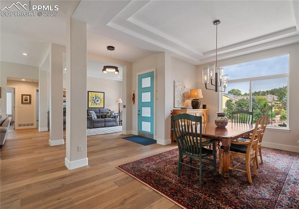 Image 6 of 50: Formal dining room has hardwood floor , tray ceiling, and newer LED lightin