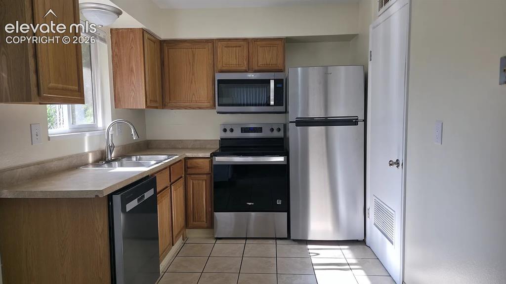 Image 2 of 5: Kitchen featuring wood cabinetry, laminate countertops, and tile flooring