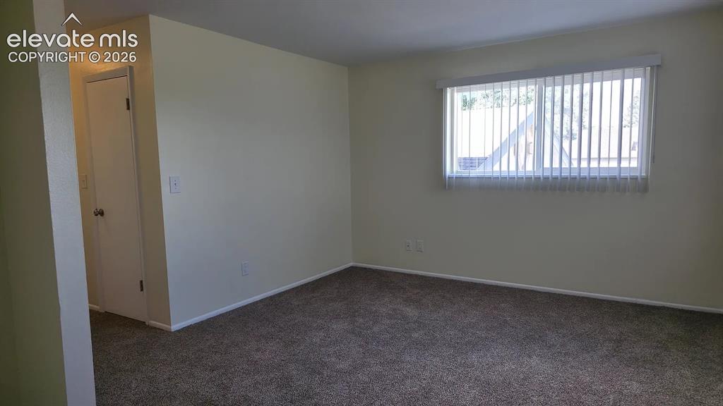 Image 3 of 5: Neutral-toned wall space with textural carpeting and a horizontal window fi