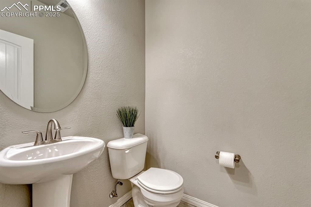Image 10 of 40: Downstairs powder room has a neutral palette and sparkling fixtures