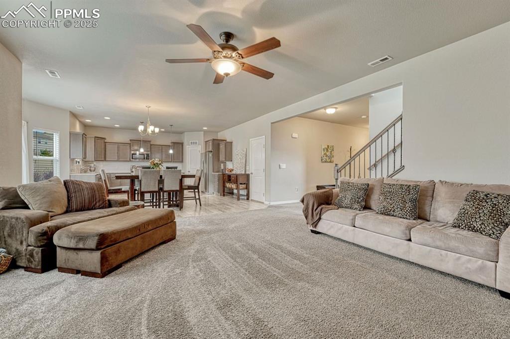Image 13 of 40: Main level great room features plush carpeting, ceiling fan and easy access