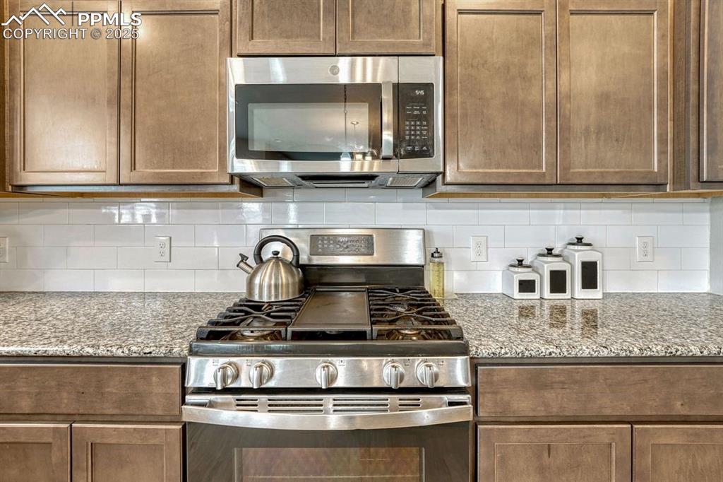 Image 16 of 40: Stainless appliances and warm tone granite counter tops along with abundant