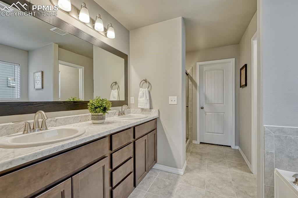 Image 5 of 40: Primary en-suite features spa like color palette, soaking tub and double si