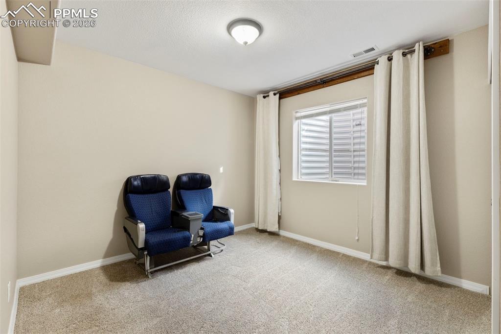Image 23 of 31: Living area with light colored carpet and a textured ceiling