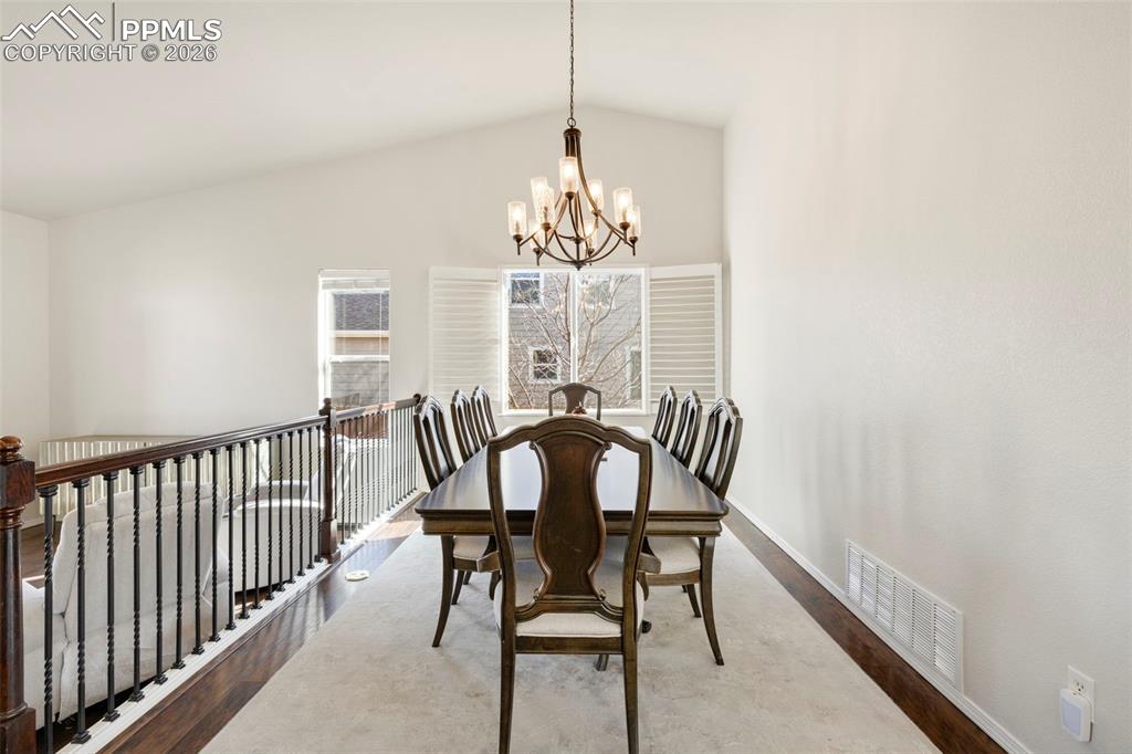 Image 7 of 31: Dining space with wood finished floors, a chandelier, and lofted ceiling